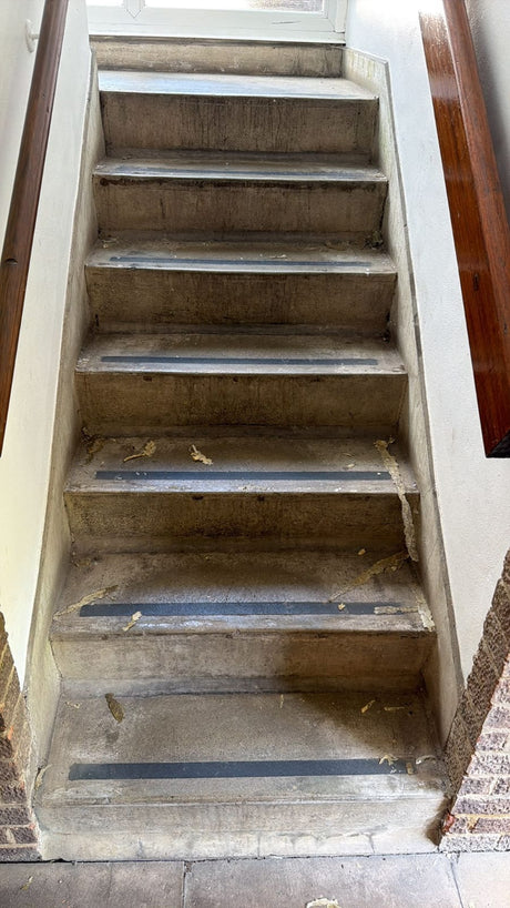 Worn concrete stair edges with damaged anti-slip strips needing replacement nosings